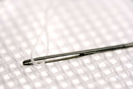 needle with thread on white canvas macro shotの写真素材