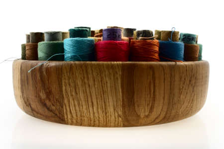 coloured threads in wooden plate isolated on whiteの写真素材