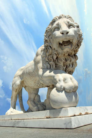 lion statue with ball over cloudy skyの写真素材