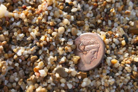 old greek copper coin in sea sand