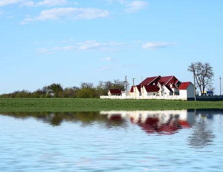 landscape with green field and house flooding in waterの写真素材