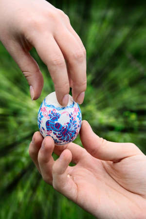 male hand giving easter color egg to woman handの写真素材