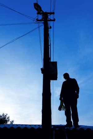 Electrician on the roof looking around before repairs power lineの写真素材