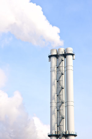 Lot of smoke from industrial smokestack over blue sky. Bad ecology concept.