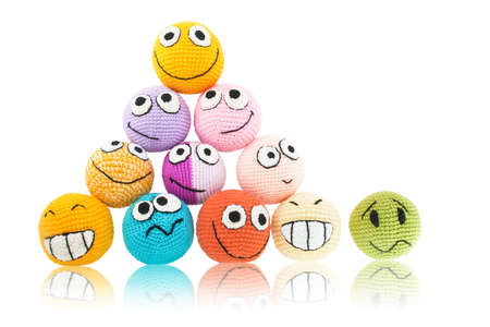 Lot of handmade colored smileys in piramide and one of them with sad face near it. Isolated on white background.の写真素材