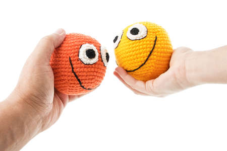 Two crochet smileys in woman and man hands looking to each other. Isolated on white background.の写真素材