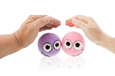 Two crochet smileys under woman and man hands protecting them. Isolated on white background.の写真素材