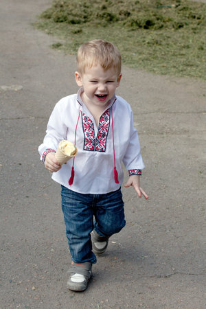 Similing small boy with ice-cream in hand and dressed on ukrainian shirtの写真素材
