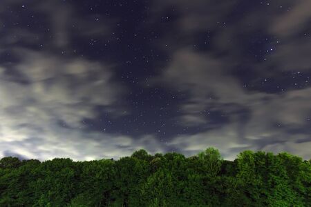 Starry Night,. White clouds, many stars, green forest. The edge of the forest. Beautiful night sky.の写真素材