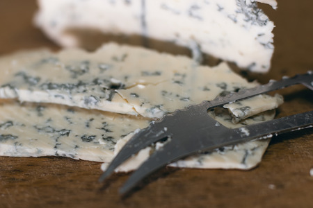 Blue cheese close up on an old wooden board and a knifeの写真素材