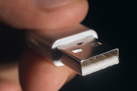 Hand holding white USB cable. Man's hand holds a USB Connector. Closeup man hand holding USB cable.Selective focus and shallow Depth of field.の写真素材