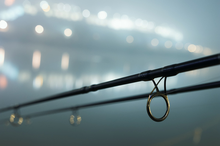 Carp spinning reel angling rods in foggy night. Urban Edition. Night Fishing, Carp Rods, City lights. Foggy night.の写真素材