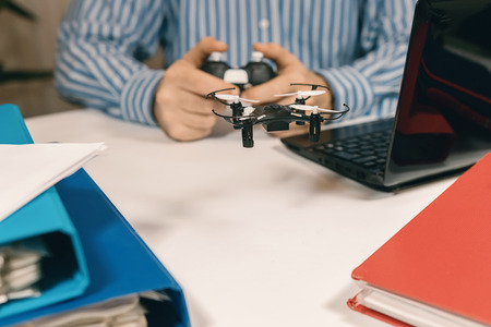Businessman playing with drone toy at the office. Businessman testing new toy on desk in office. Office playing.の写真素材
