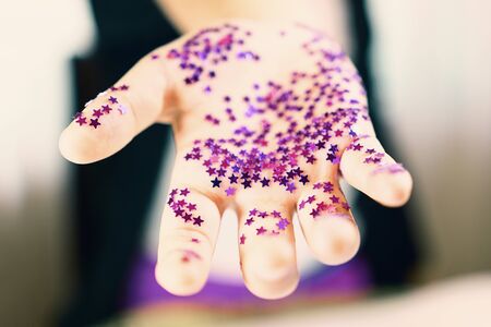 Offering hand. Offering friendship. Stardust and magic in hand. Girl hand holding shiny confetti starsの写真素材
