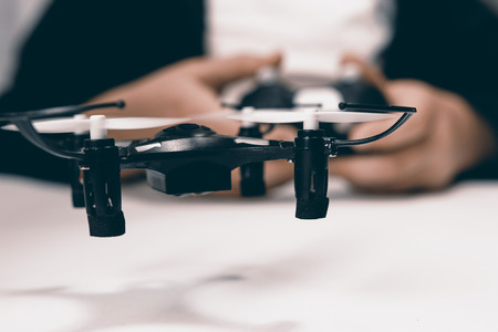 Boy hands with a remote control flying a small drone toy indoors.の写真素材