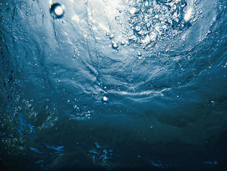 Underwater bubbles sunlight through water surface. Underwater background.