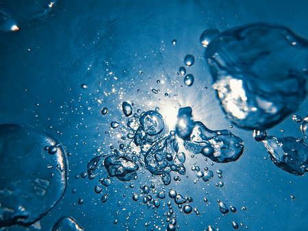 Underwater bubbles sunlight through water surface. Underwater background.の写真素材