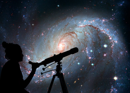 Girl looking at the stars with telescope. Stellar Nursery NGC 1672. Spiral galaxy in the constellation Dorado.の写真素材