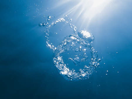 Bubble ring underwater ascends towards the sun.の写真素材