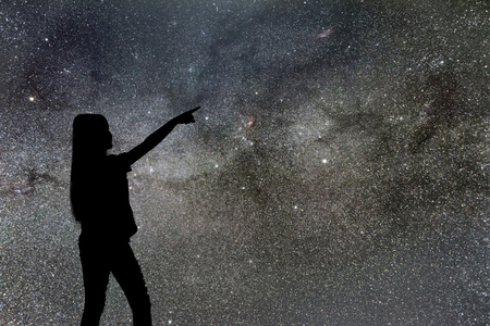 Silhouette of woman stand alone in the night milky way and stars field backgroundの写真素材