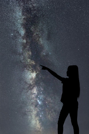 Silhouette of woman stand alone in the night milky way and stars field backgroundの写真素材