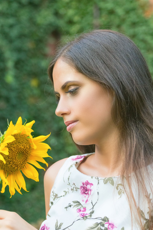 Close-up portrait of brunette woman with sunflower in her handの写真素材