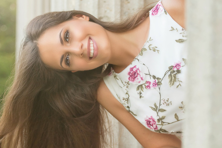 Beautiful brunette young woman wearing nice dress flower pattern. Fashion photo.の写真素材