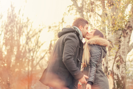 Couple in love autumn, Man kissing a woman, fallen leaves in a park, beautiful autumn dayの写真素材
