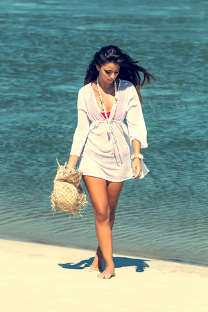 Beautiful woman on tropical beach, Brunette tanned girl enjoying and walking on beachの写真素材