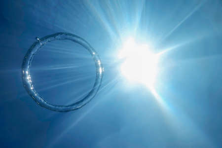 Underwater Bubble Ring Ascends towards the Sunの写真素材