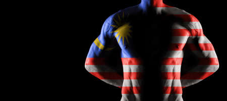 Malaysia flag on muscled male torso with abs, black backgroundの写真素材