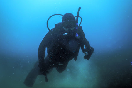 Scuba Diver Swimming on a Blue Water looking at camera