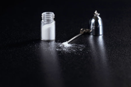A small glass bottle containing a white powdery substance on a black background.
