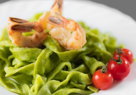 Spinach pasta with shrimp and cherry tomatoes close-upの写真素材