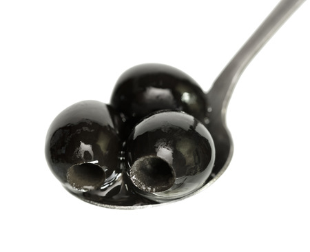 Olives in a spoon closeup on white background isolatedの写真素材