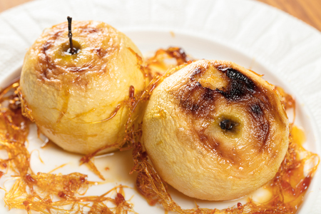 two baked apples with caramel on a plate の写真素材