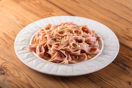 pink spaghetti cooked in a sauce on a wooden backgroundの写真素材