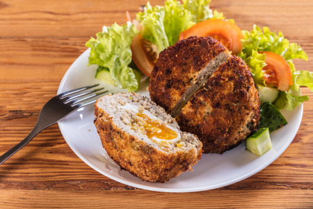 scotch egg with vegetables on a wooden background