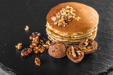 Pancake with fresh walnuts on a black surfaceの写真素材
