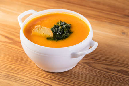 Carrot cream soup puree on a wooden background