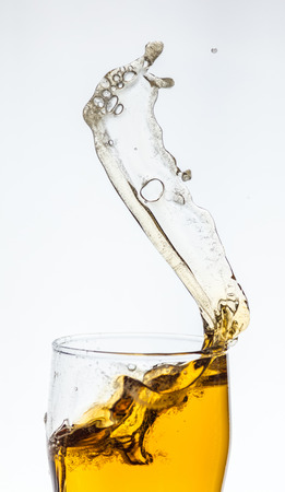 Splashing beer from a glass on white backgroundの写真素材