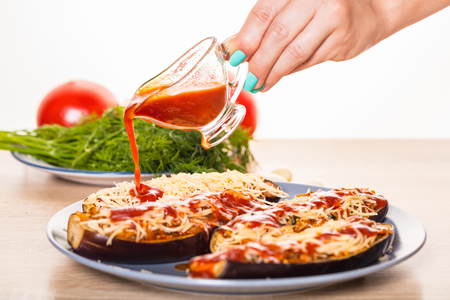 Cook pours tomato sauce on stuffed eggplantの写真素材