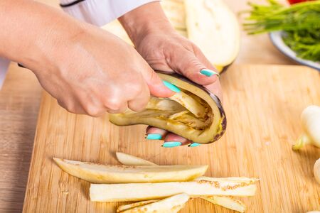 The cook cuts the eggplant with a knifeの写真素材