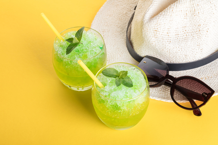 Cocktail mojito and hat on a yellow backgroundの写真素材
