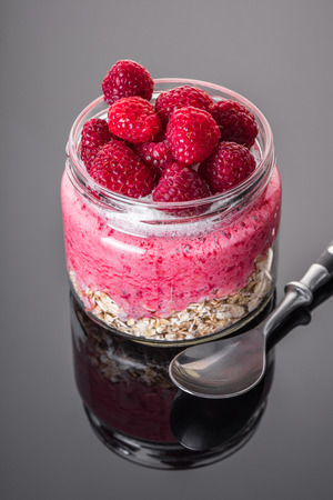 Oatmeal with raspberry in jar, black background with reflectionの写真素材