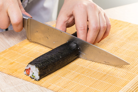 Japanese cuisine. Chef cuts rolls, hands close-upの写真素材