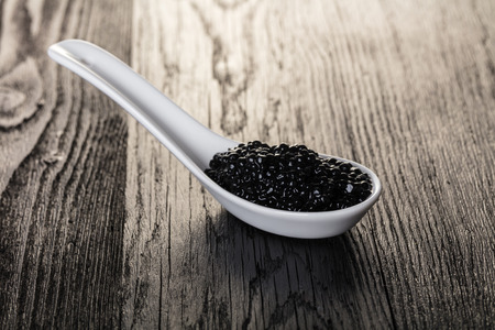 black caviar in a spoon on wooden backgroundの写真素材