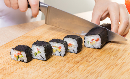 Japanese cuisine. Chef cuts rolls, hands close-upの写真素材