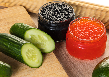 black and red caviar in a jar with vegetablesの写真素材