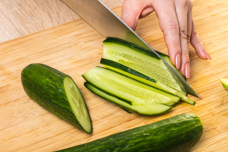 chef cuts cucumber with a knife, close-up handsの写真素材